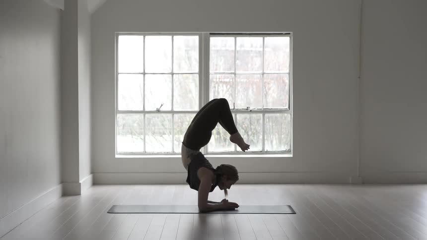 A woman stretches in a white room