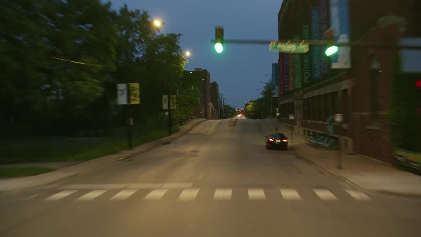 Traveling on a city street at dusk and there is only very light traffic and the street lights are on