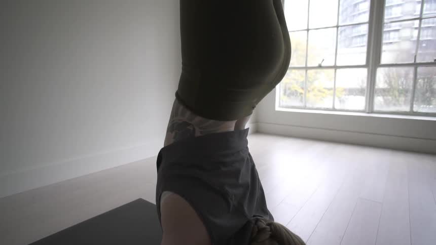 A woman is doing a handstand on a yoga mat