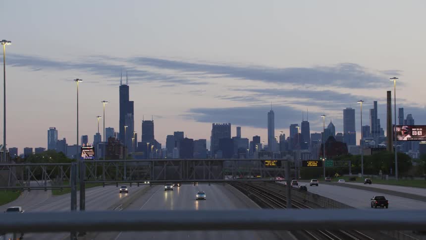 A distant view of cars driving toward and away from the chicago city skyline