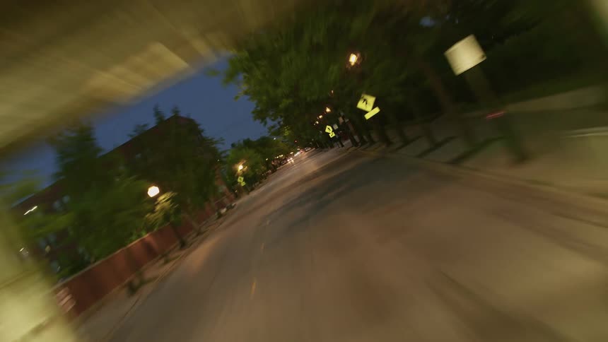 Rotating timelapse driving through a well-lit tunnel under a elevated train track into a neighborhood at night
