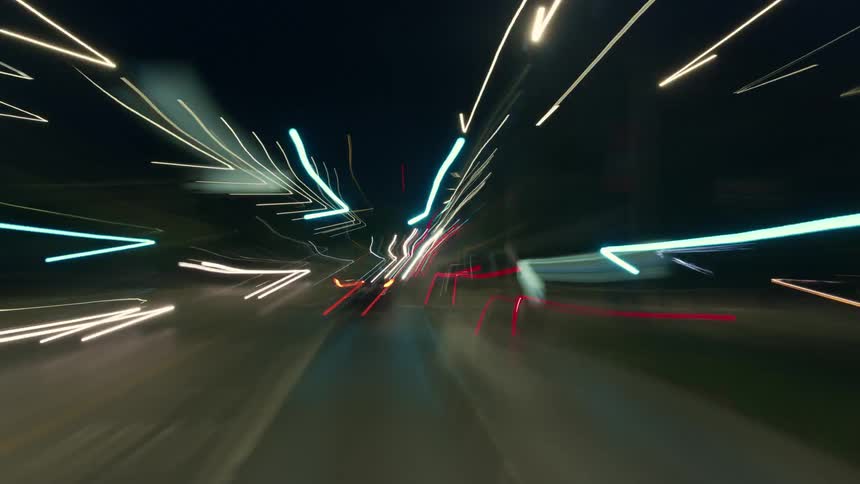 The lights of vehicles and buildings blur past at super speed