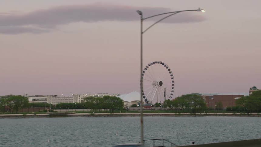 A carnival with a big tent and ferris wheel is set up near a river