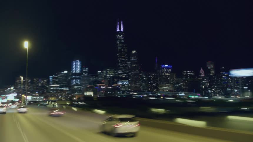 Timelapse of traffic passing by downtown chicago on a multi lane highway at night