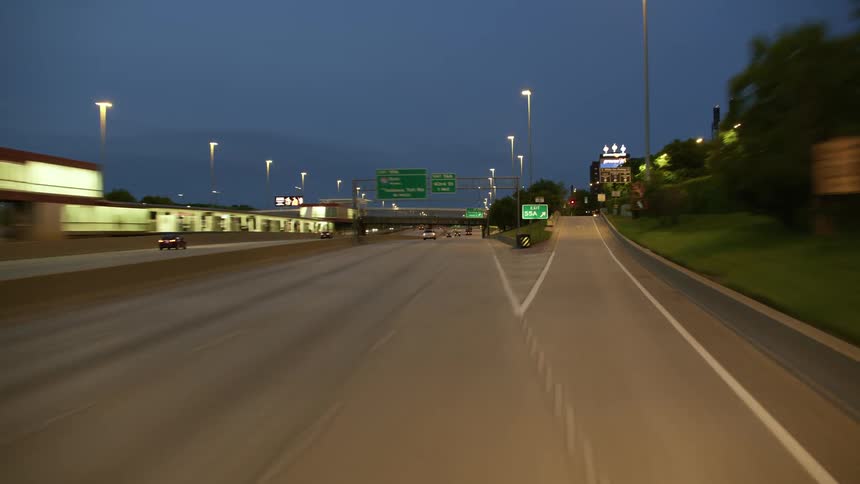 Vehicles drive on the highway past the city