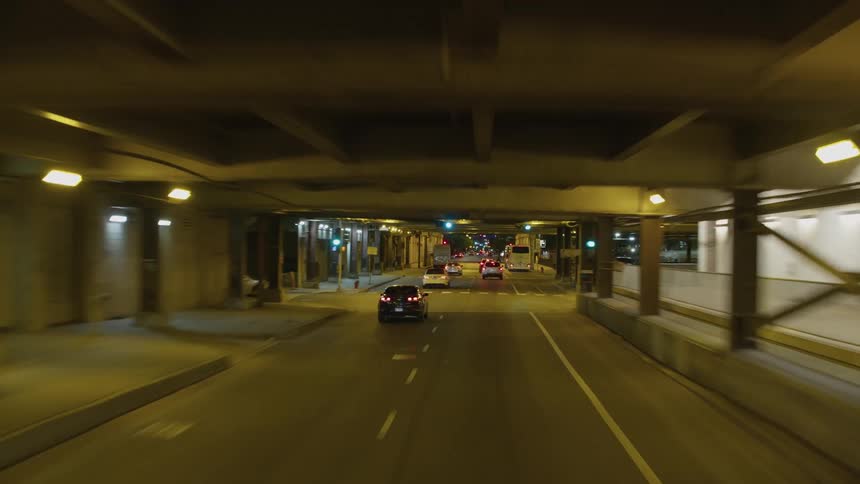 Footage of vehicles driving down the city street under bridges and overpasses at night
