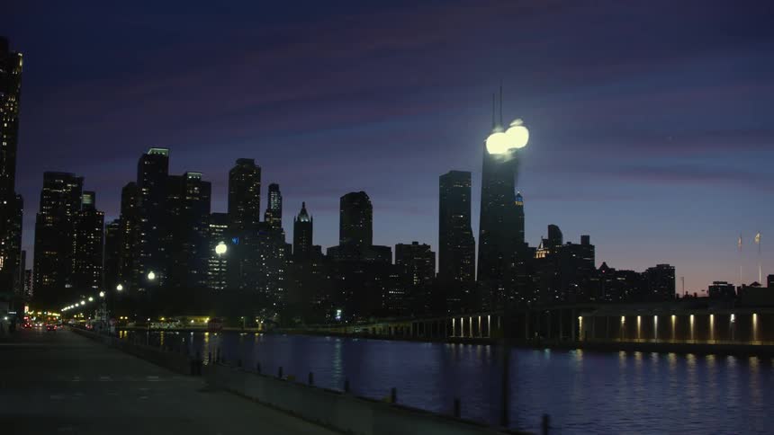 Silhouette of the chicago city skyline over. the river at night