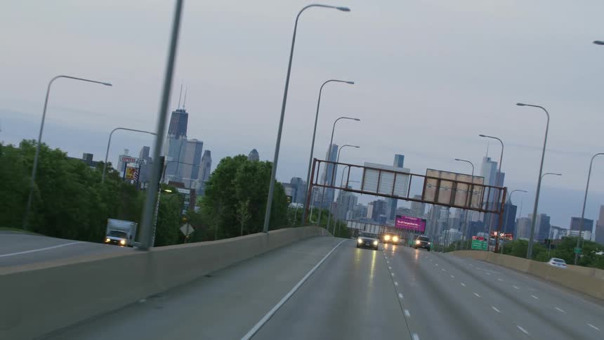 City skyline rotates in the background as vehicles drive away from chicago