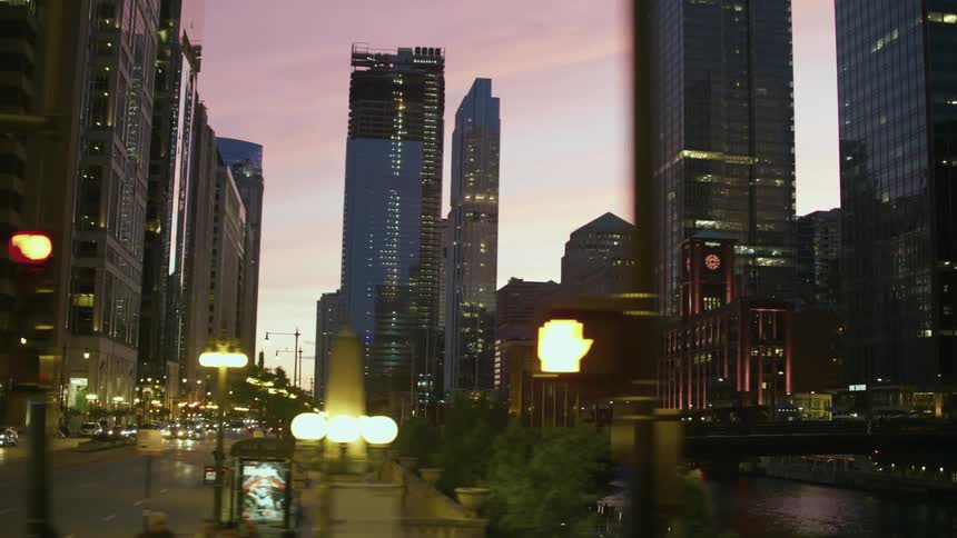People walk along the chicago riverfront in the evening next to heavy traffic in a city