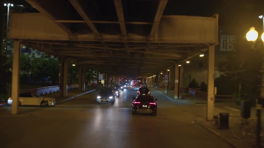 Twisting footage of vehicles driving down the city street under the metro train tracks