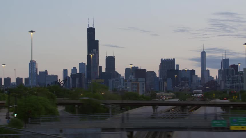 Vehicles drive on a highway passing the downtown city skyline of chicago