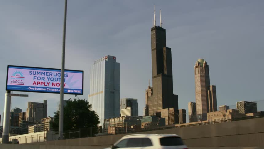 Traffic moves on the highway with the tall city buildings of chicago in the distance