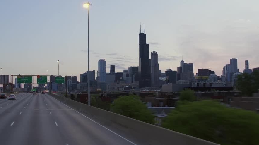 Vehicles travel on the highway past the city skyline