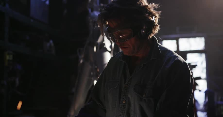 Sparks fly around a welder in a workshop