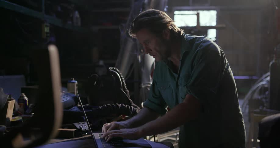 A man types on a laptop in a workshop