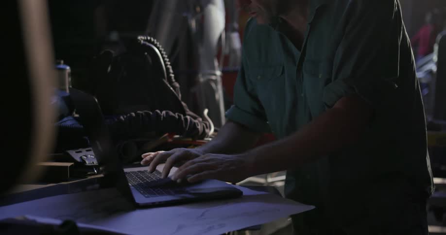 Man types on a laptop in a garage