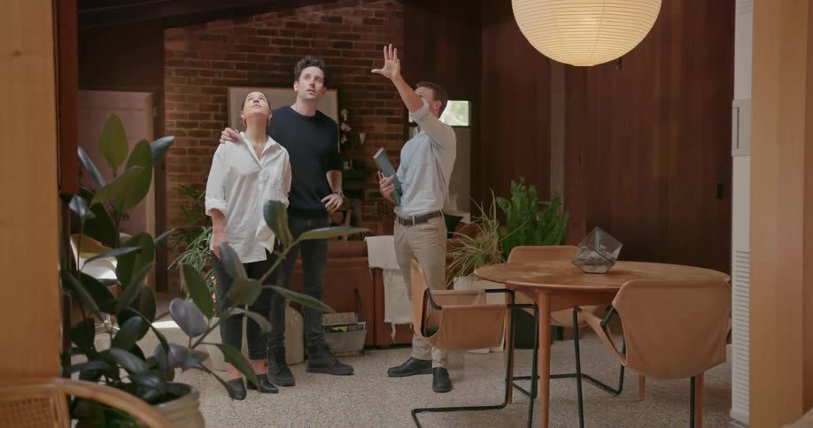 Two men and a woman are having a discussion and looking at things in a room