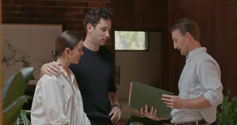 A salesman is talking to a couple inside a home
