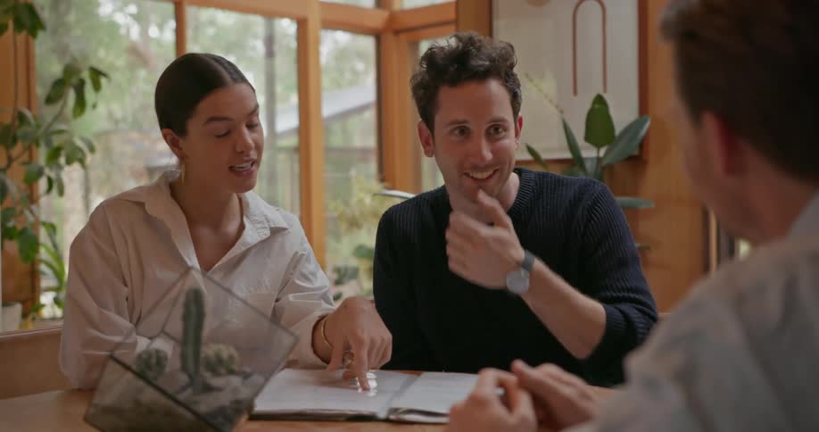 A man and a woman are talking to a man at a desk