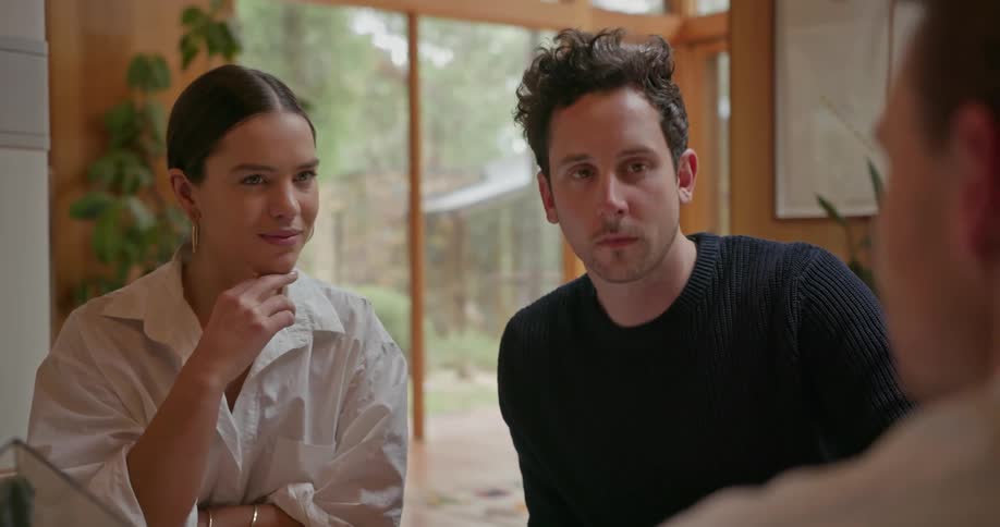A couple and another man are having a discussion at a table