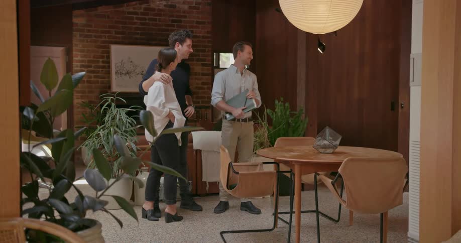 Two men and a woman look at the inside of a house
