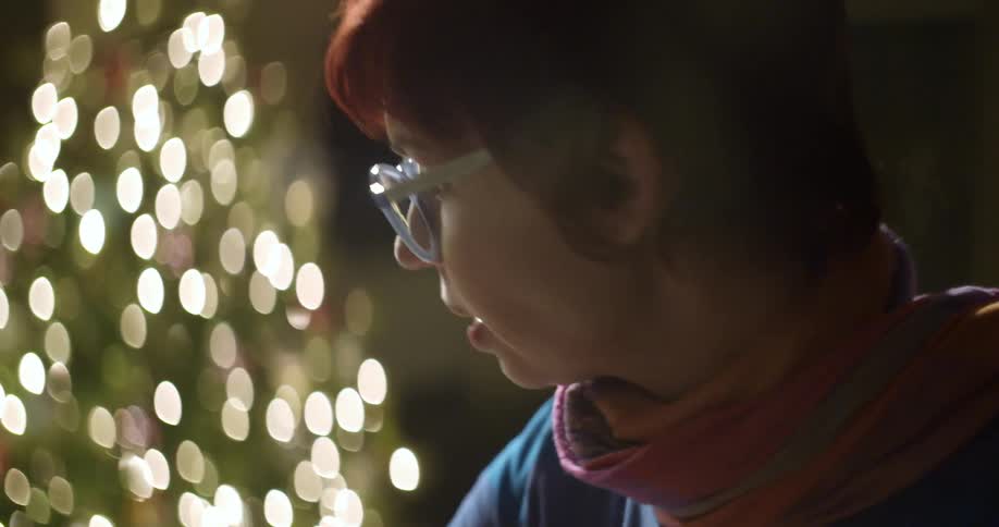 A woman is talking to someone as she stands in a room with a christmas tree