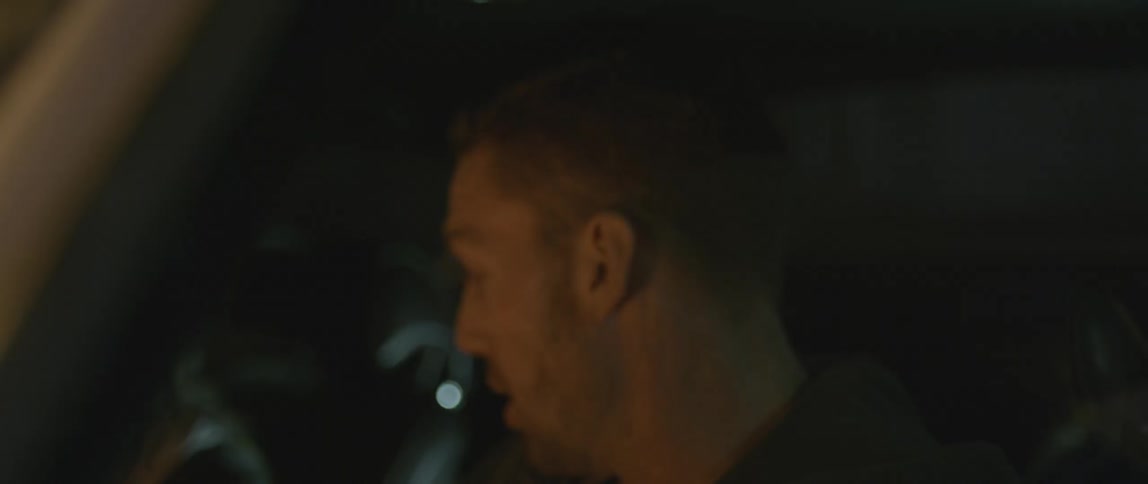 A man and woman in a car argue over a briefcase full of money