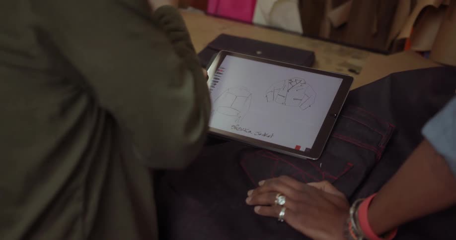 Two men look at a tablet and one touches black cloth