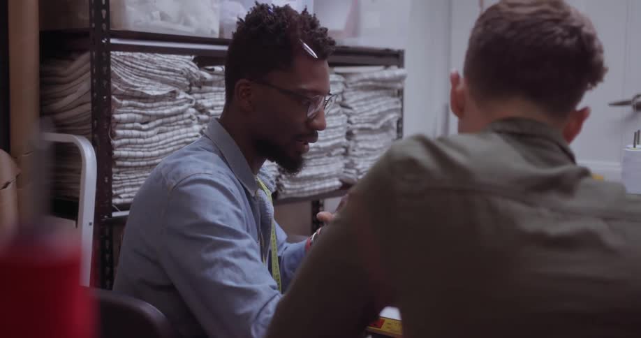 Two men talking near a rack of cloth