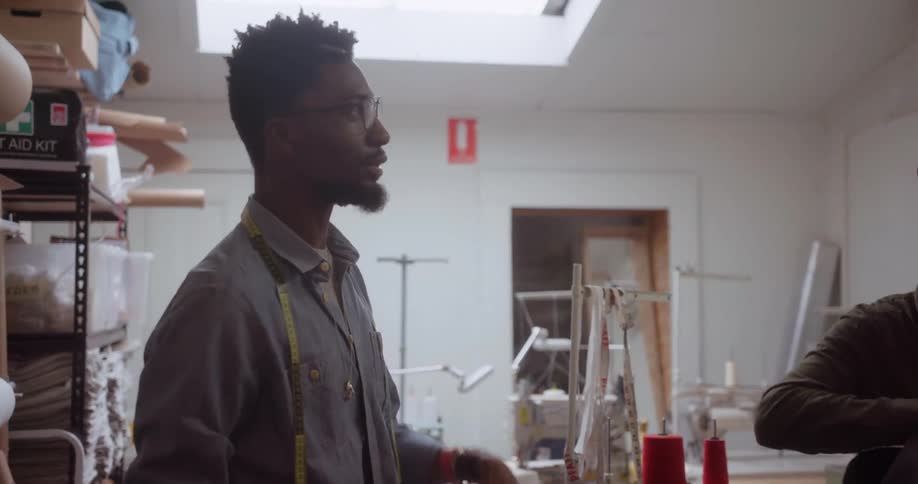 Two men are talking as they work in a sewing room