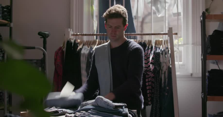 A man is folding jeans in a store