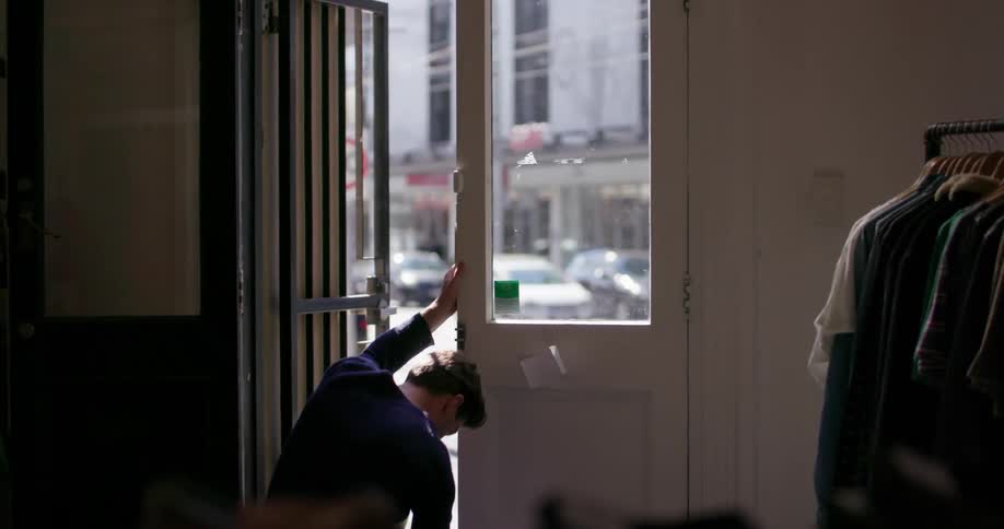 Man closes a clothing store door and locks it