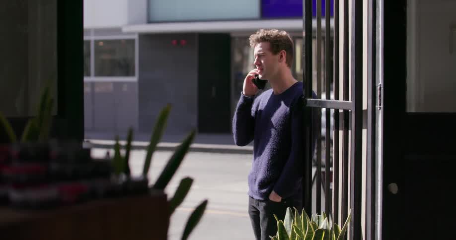 A man talks on his phone outside a shop door
