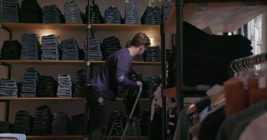 A man stocks shelves in a clothing store