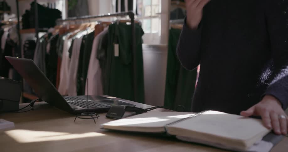 A man uses a laptop and flips through a book
