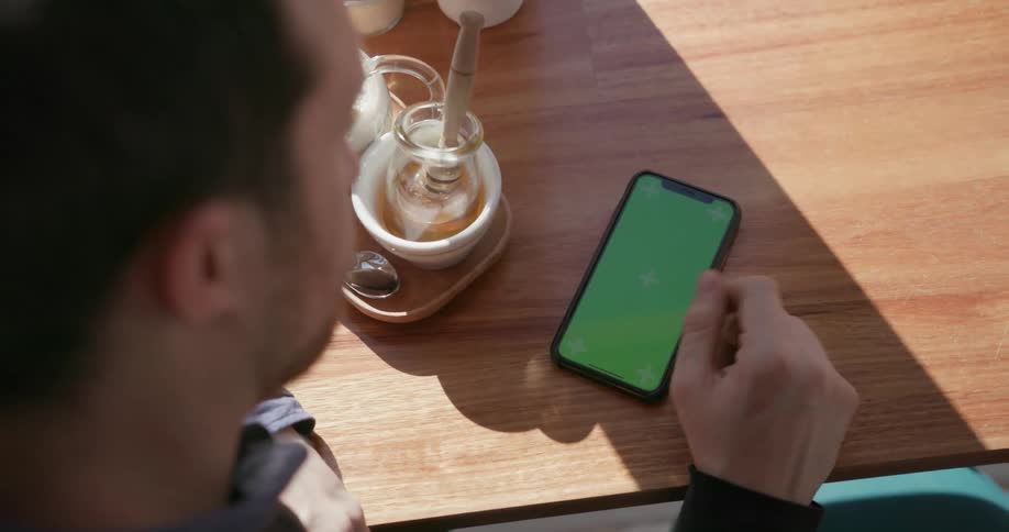 Man looks at a cell phone sitting on a table