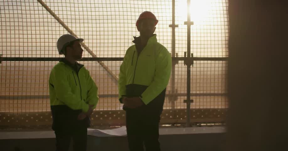 Two contractors in a fenced in area