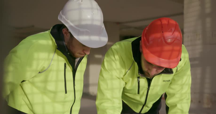 Two workers talk together looking at a blueprint