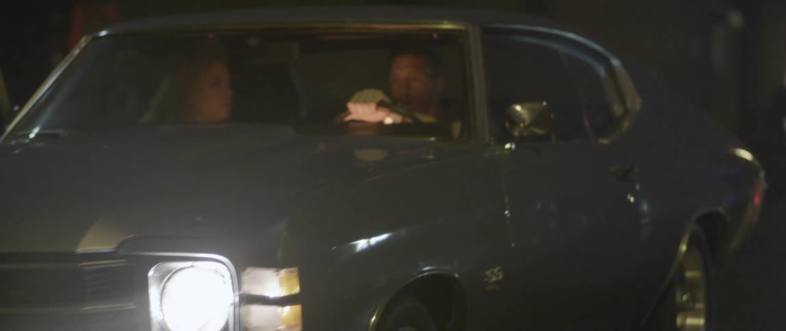 A man and woman in a car at night