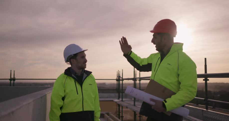 Two men in hardhats are having a discussion about work