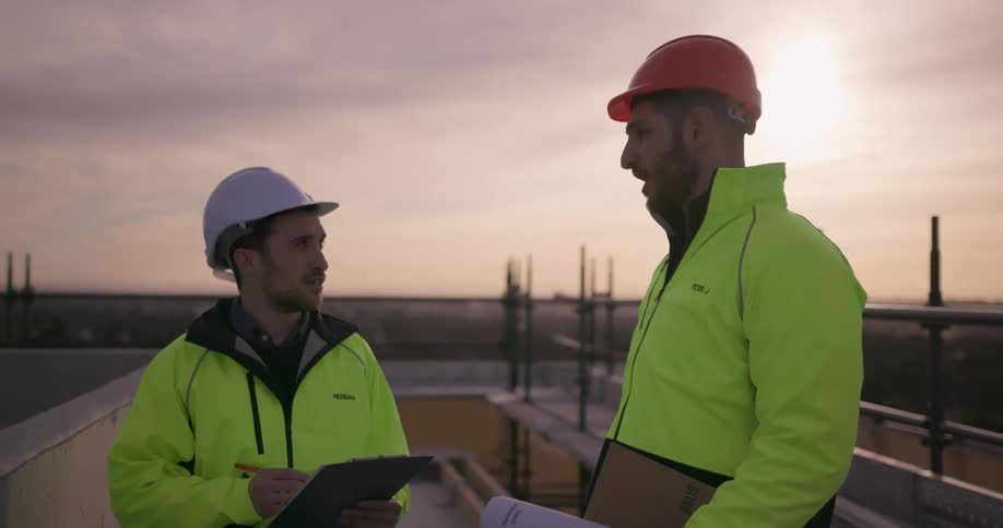 Two workers talk at a construction site