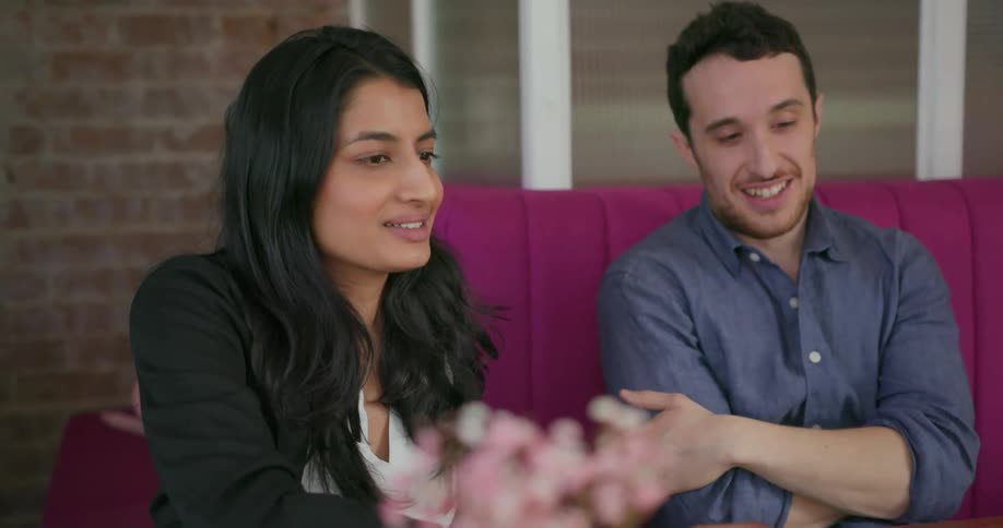 A man and woman are looking at a laptop and laughing