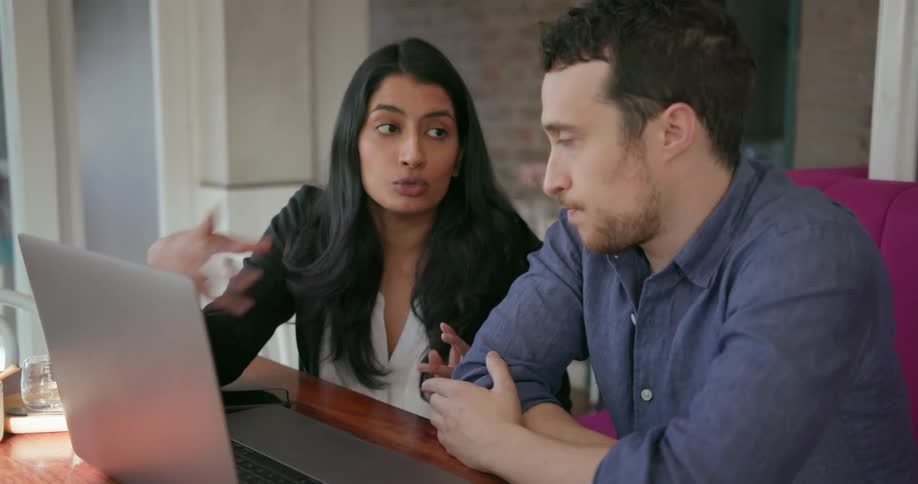 Man and woman talk while looking at a laptop