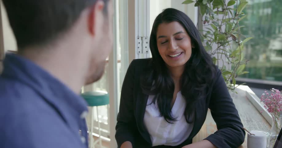 A woman talks with a man by the window