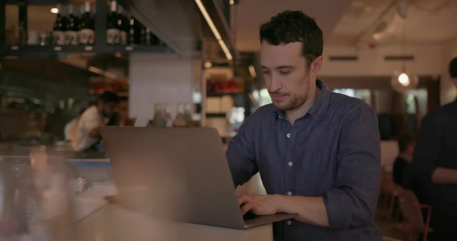 Man types on a laptop in a restaurant