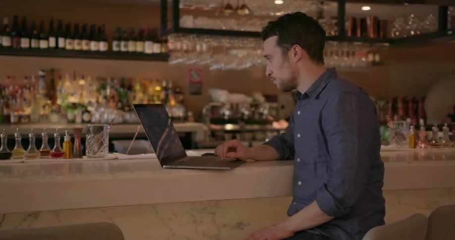 A man uses a laptop at a bar