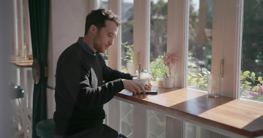 A man is sitting at a bench looking at his phone