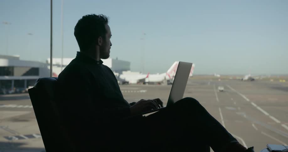 A man sits in an airport with a laptop
