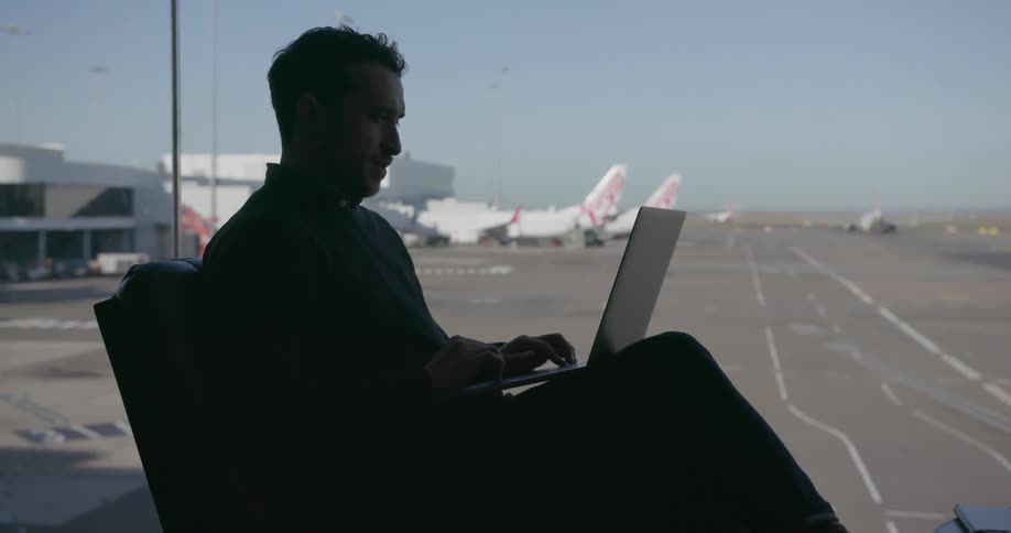 A man works on a laptop in an airport