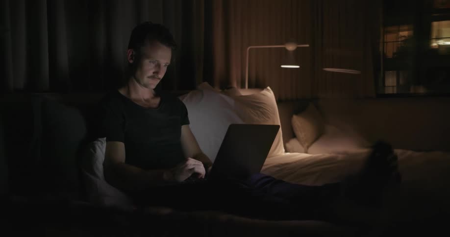 A man is sitting on the couch working on his laptop